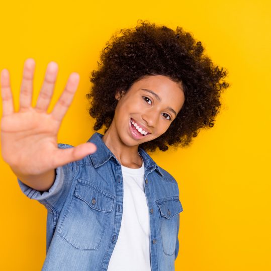 Portrait of attractive cheerful teen-aged girl giving five perfect isolated over bright yellow color background.